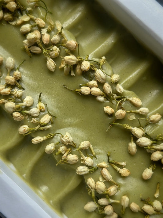 freshly poured green cold process soap top decorated with dried jasmine