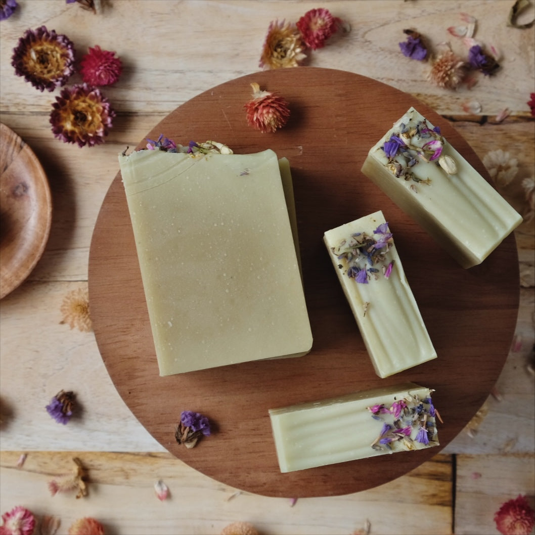 4 light green Coconut milk soaps scented with  lavender, ylang ylang, frankincense and cedarwood atlas, on wooden stand.