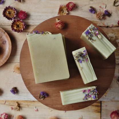 4 light green Coconut milk soaps scented with  lavender, ylang ylang, frankincense and cedarwood atlas, on wooden stand.
