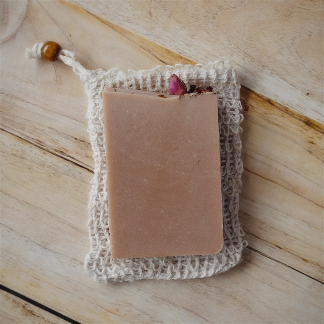 all natural sisal fiber soap saver bag with a brown bead and a bar of soap to compare size.