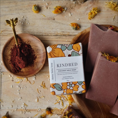 All natural soap bars colored with Moroccan red clay and scented with clove, cedarwood atlas, and patchouli essential oils and decorated with dried wild flowers. Soap is wrapped in decorative floral paper.