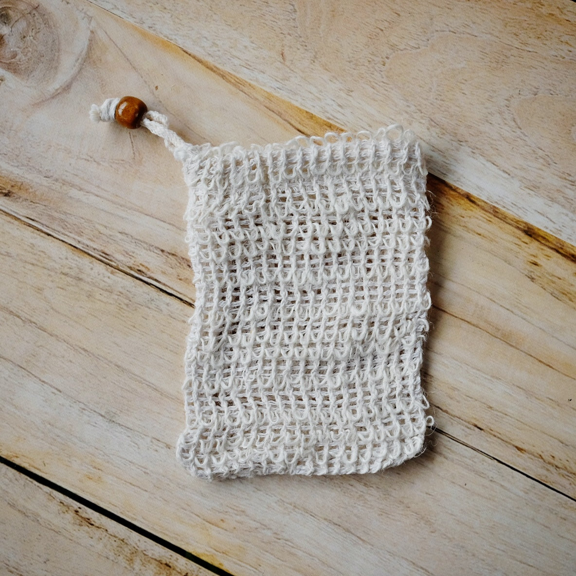 all natural sisal fiber soap saver bag with a brown bead. 