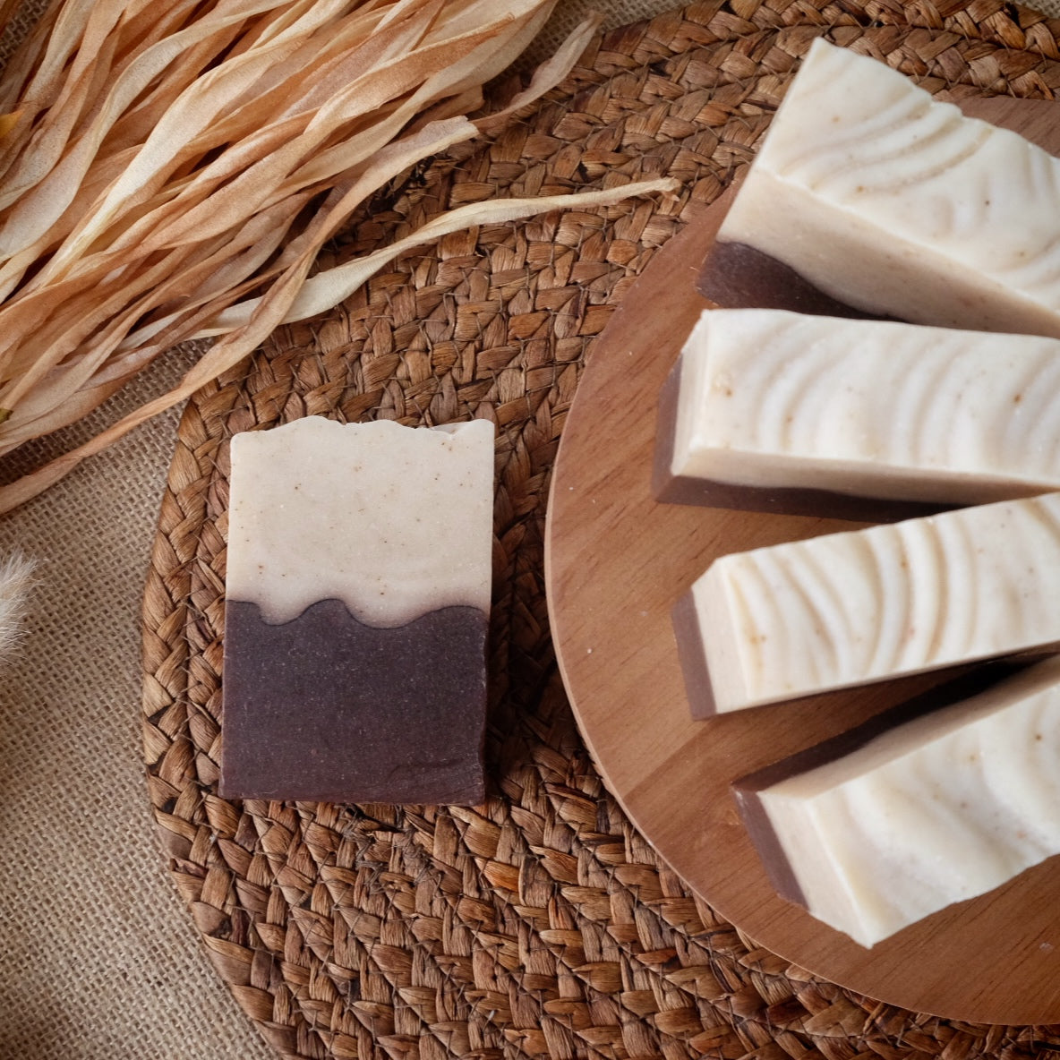 Handmade soap bars with a layered design on a woven mat